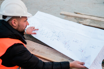 Engineering Consulting on construction site holding blueprint in his hand. Building inspector. Construction site check drawing and business workflow of the project.