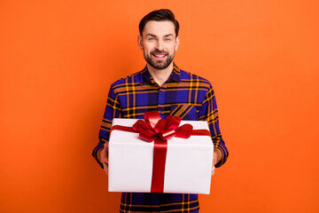 Photo of satisfied young man hands hold giftbox beaming smile look camera isolated on orange color background