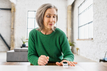 Aged healthy woman with wrinkles on the face, dressed in green warm sweater, determines the...
