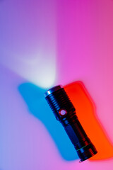Fototapeta na wymiar A small black flashlight in colored lighting. 