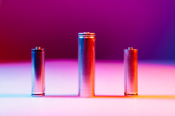 AA and 8650 Li-ion silver batteries on illuminated by multicolored light 