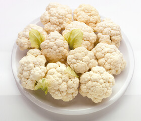 Coliflor  cruda sobre fondo blanco, vista cenital. Raw cauliflower on white background, overhead view.