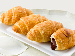 Croissant relleno de chocolate sobre bandeja, vista cenital, pastelería. Chocolate filled croissant on tray, overhead view, pastry.