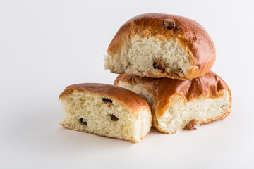 Two sweet buns with raisins with a cut piece on a white background, isolated. Close-up with a copy space for the text.