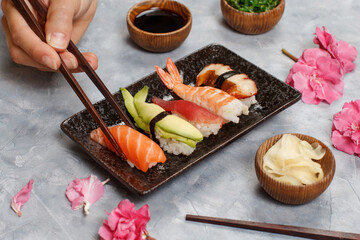 Close up of hand taking roll with chopsticks from a plate