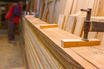 Squeezing with industrial metal f-clamp after gluing wooden profiles in workshop