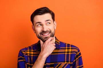 Photo of young cheerful man happy positive smile hand touch chin dream think look empty space isolated over orange color background
