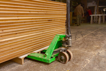 Manual forklift loaded with wooden, glued profiles in warehouse of carpentry © Roman_23203