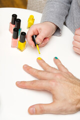 Girl paints her dad's nails with various colors. LGBT family concept