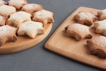 Delicious homemade cookies in the shape of stars sprinkled with sugar. Laid out on a kitchen board on a dark gray background.