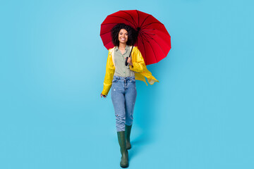 Full body photo of young afro woman happy positive smile go walk rainy wet hold parasol isolated...