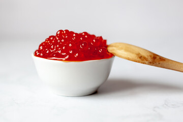 a wooden spoon rests on a white cup full of red caviar