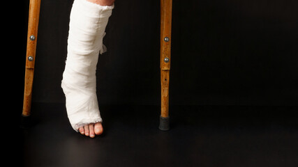 Leg in a cast and two crutches on a black background