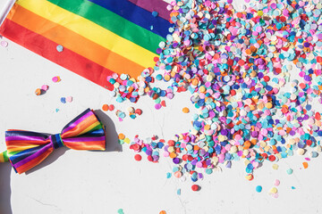 background for lgbt party. a flag with a bow tie and confetti in the colors of gay pride. top view