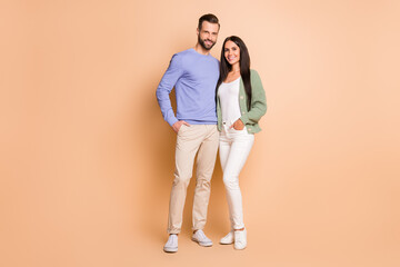 Full length body size view of attractive cheerful couple soulmates embracing isolated over beige...