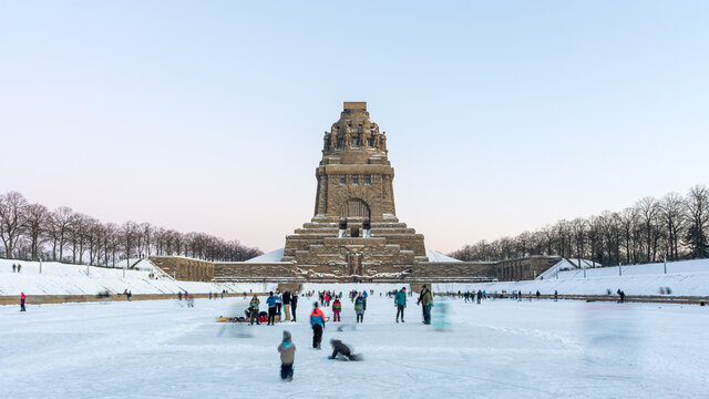 Leipzig, Germany - 02.13.2021: People playing ice hockey and skating on ice in front of the Monument to the Battle of the Nations