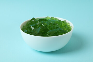 Bowl of kiwi jelly on blue background