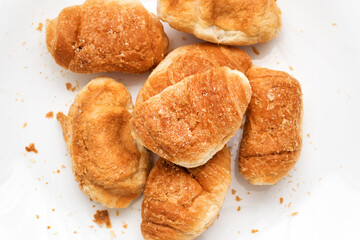 Stack of golden colored baked buns lying on white table of kitchen