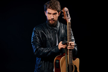 A man with a guitar in his hands leather jacket music performance rock star modern style dark background