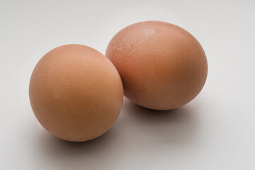 Two boiled or raw fresh eggs in yellow shell isolated on white background