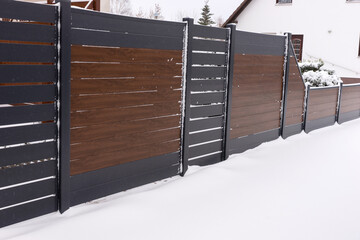 New stylish high plastic fence in winter. Vinyl products. Protection of the house