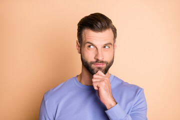 Photo of optimistic brunet guy hand chin look empty space wear sweater isolated on beige color...
