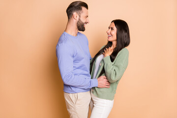 Photo of young happy positive smiling cheerful couple look each other talk speak isolated on beige color background