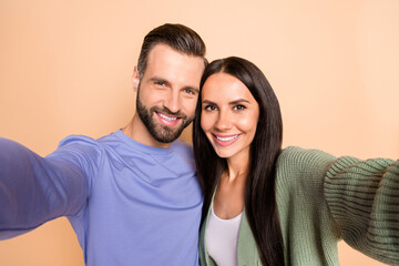 Obraz premium Photo of young happy positive smiling cheerful couple wife and husband taking selfie isolated on beige color background