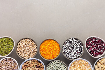 Different types of legumes in bowls, green and yellow peas, chickpeas and peanuts, colored beans...