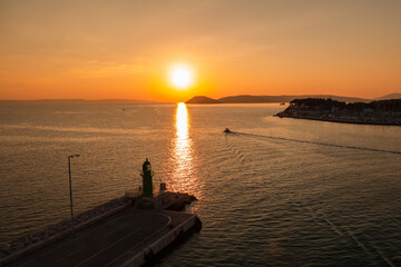 Sunset over the Adriatic Sea and its boats playing in the reflections at the entrance to the port of Split in Croatia