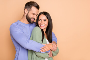 Photo of optimistic couple hug look with empty space wear cardigan sweater isolated on beige color background