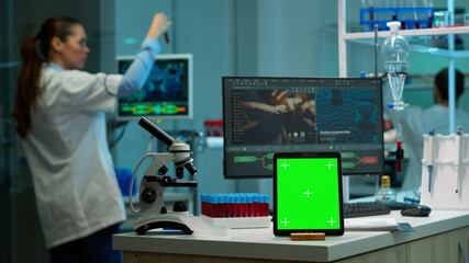 Team of scientists working in background of modern laboratory using tablet with green screen, mockup display, isolated chroma key monitor, analysing experiment evolution, high tech development lab.