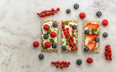 Naklejka na ściany i meble Snack with rye oats crispbread, cottage cheese, and fresh berries on a marble table.