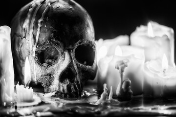 Candles and human skull in darkness closeup in black and whiter