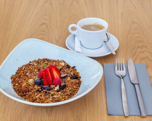Muesli bowl with berries on top served with a cup of espresso on the side. Perfect breakfast in the morning.
