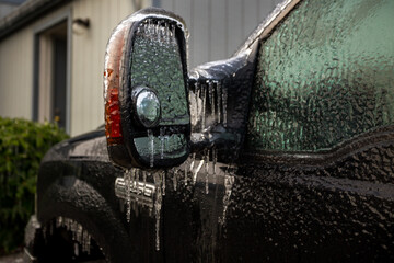 An icy-covered vehicle mirror and other parts of car after an ice storm
