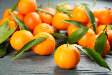 Fresh ripe tangerines with green leaves on grey wooden table