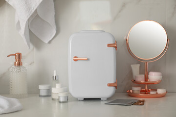 Fototapeta na wymiar Cosmetics refrigerator and skin care products on white table indoors