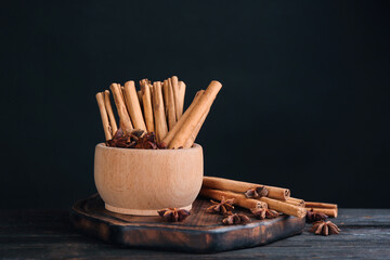 Aromatic cinnamon sticks and anise on black wooden table