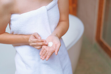 Woman applying cream,lotion on hand with wood background, Beauty concept.