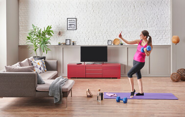 Fototapeta na wymiar Sportive woman is doing training at home, purple mat, blue dumbbell, decorative living room concept. Healthy lifestyle.