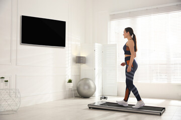 Sporty woman training on walking treadmill at home