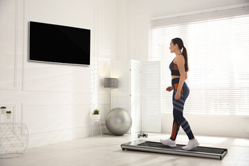 Fototapeta na wymiar Sporty woman training on walking treadmill at home