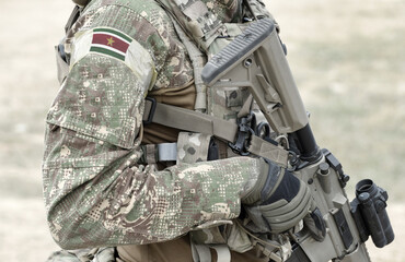 Soldier with assault rifle and flag of Suriname on military uniform. Collage.