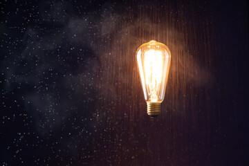 levitating light bulb glows without wires. on the background the effect of rain and smoke