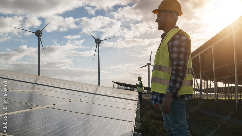 Wall mural Man working for solar panels and wind turbines - Renewable energy concept - Focus on male worker face