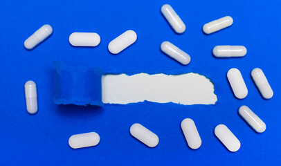 White pills lie on a beautiful blue background. Copy space. Medical concept. View from above.