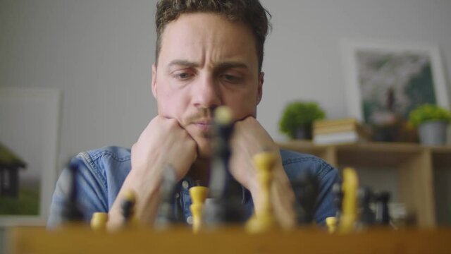 A young handsome guy is thinking about the next move in a difficult game