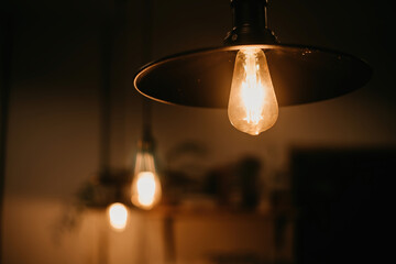 Light bulb Orange incandescent lamp hanging in low light.