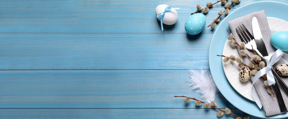 Festive Easter table setting with eggs on light blue wooden background, flat lay. Space for text